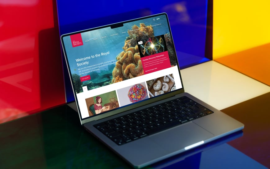 laptop displaying the Royal Society website with colourful background